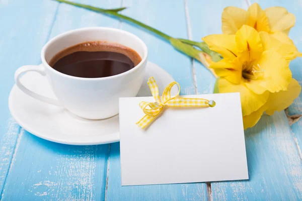 Leere Papierkarte, Kaffee und gelbe Blume auf blauem Holz — Stockfoto