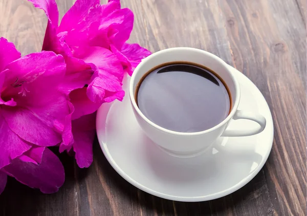 Tasse schwarzen Kaffee und rosa Blumen — Stockfoto