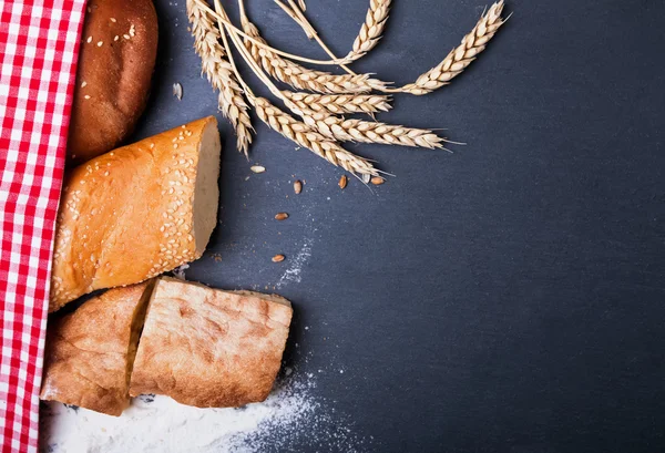 Different kinds of bread, wheat and flour on the black backgroun — Stock Photo, Image