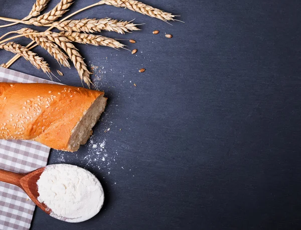 Wheat, baquette and flour on the black board — Stock Photo, Image