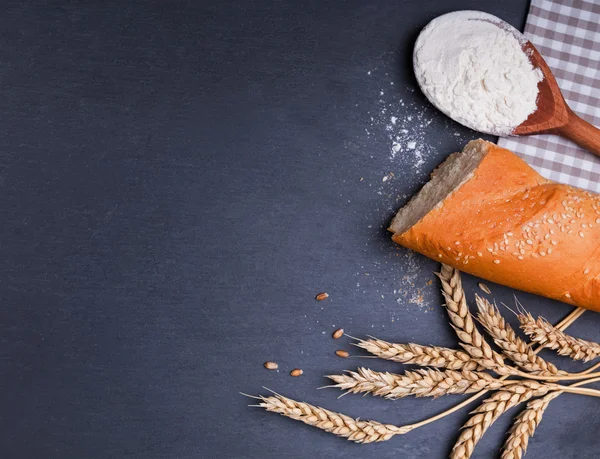 Bread, flour and wheat ears on the black board — Stock Photo, Image