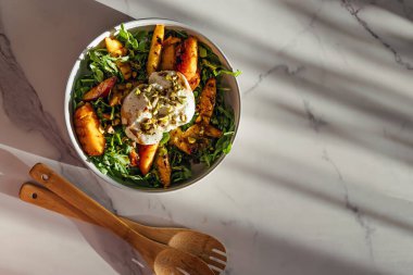 Fıstıklı ızgara şeftali, taze yeşillik ve kremalı burrata içeren canlı bir salata..