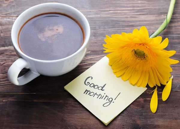 Fincan kahve, sarı gerbera çiçek ve kağıt ile metin "iyi m — Stok fotoğraf