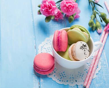 Macarons  and pink flowers on the table close-up
