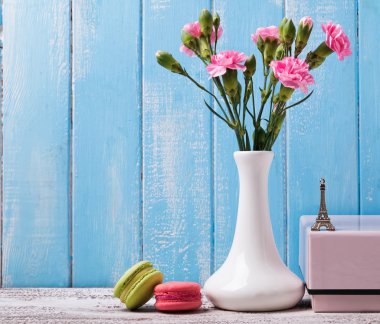 Pink flowers in the vase, macarons and souvenir Eiffel tower
