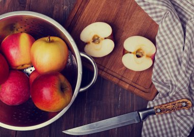 Appels in a strainer, knife and napkin on the wooden table
