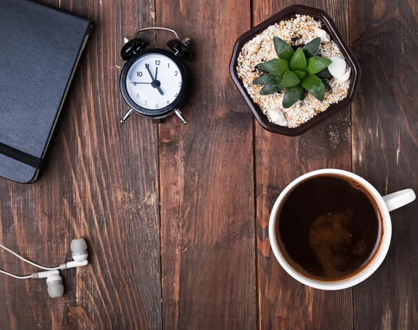 Caffè, sveglia, succulente impianto e auricolari sul tavolo — Foto Stock