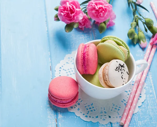 Macarons und rosa Blumen auf dem Tisch in Großaufnahme — Stockfoto