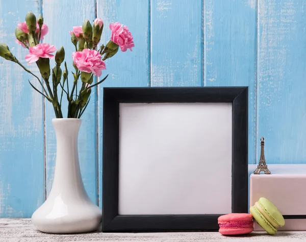 Blank frame, pink flowers and macarons. — Stock fotografie