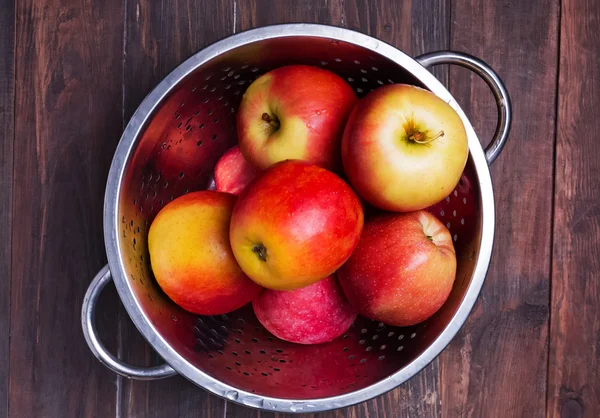 Red apples in a strainer on the wooden table — 스톡 사진