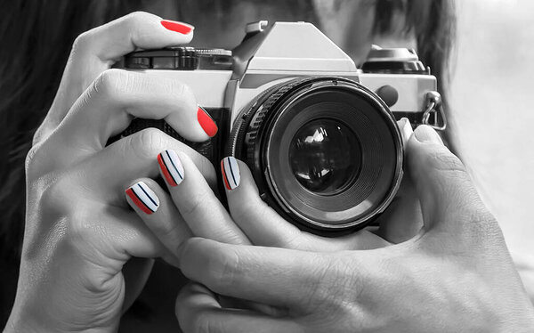 Photographer SLR camera with lense reflections. Black and white portrait woman with red nail manicure