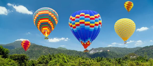 Hot air balloons colorful landing in a mountain. Ballooning panoramic nature landscape of countryside mountains in summer sky