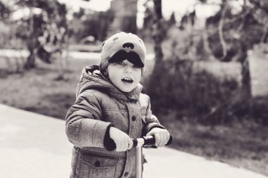 açık havada bahar içinde scooter üzerinde yürümeye başlayan çocuk