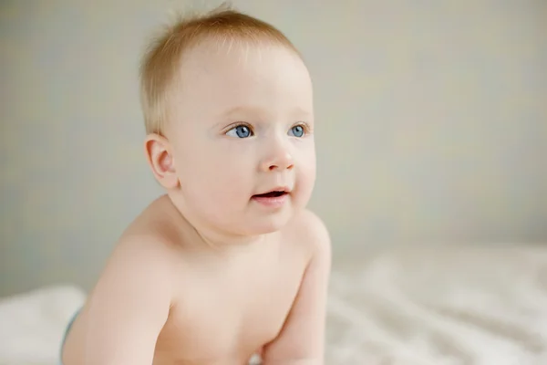 Bebê de olhos azuis sentado no sofá — Fotografia de Stock