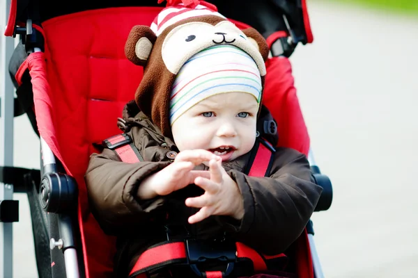 Babyjongen in rode wandelwagen — Stockfoto