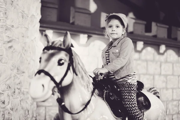 Meisje rijdt een carrousel paard — Stockfoto