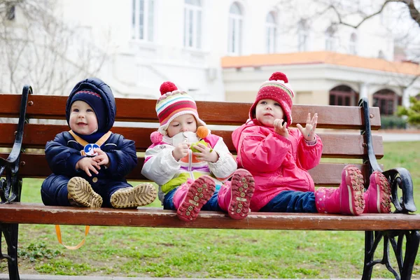 Tres niños pequeños en el banco —  Fotos de Stock