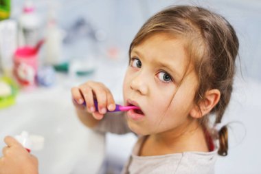 Banyoda dişlerini fırçalayan küçük kız.