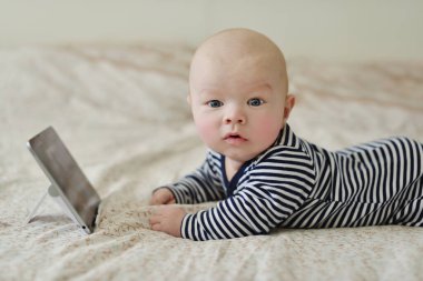 Yatağında tablet olan bebek.