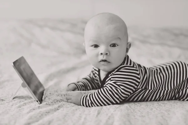 ベッドの上にタブレットPcを持っている赤ちゃん — ストック写真
