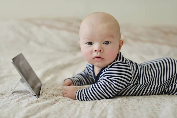 ベッドの上にタブレットPcを持っている赤ちゃん — ストック写真