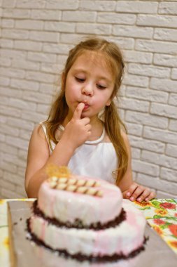 Çocuk kız parmaklarıyla pasta yiyor.