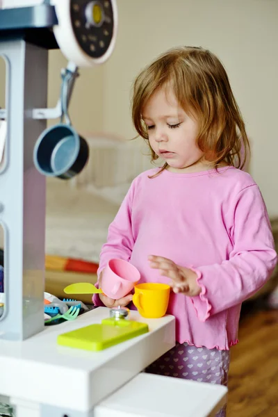 蹒跚学步的女孩玩玩具厨房 — 图库照片
