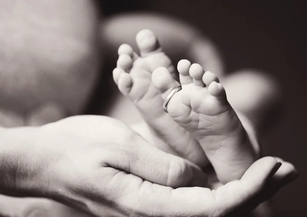 Pie del recién nacido en la mano materna — Foto de Stock