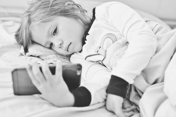 Niña en la cama con teléfono inteligente — Foto de Stock