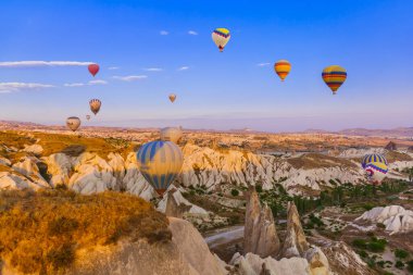 Kapadokya, Türkiye - 31 Ağustos 2011: Kapadokya 'da güneş doğarken kayalık arazide uçan sıcak hava balonu.