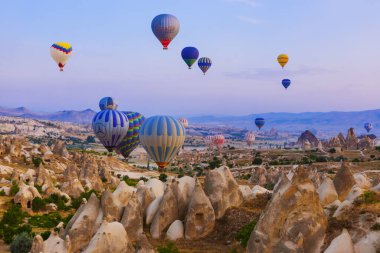 Kapadokya, Türkiye - 31 Ağustos 2011: Kapadokya 'da güneş doğarken kayalık arazide uçan sıcak hava balonu.