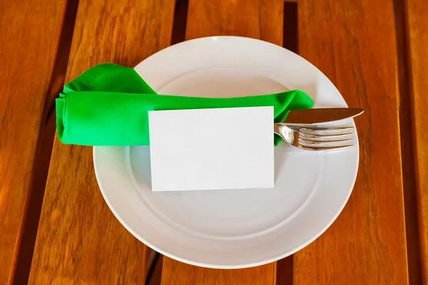 Louça e cartão de papel em branco na mesa no restaurante — Fotografia de Stock