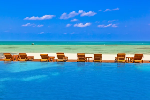 Solstolar och pool på Maldiverna strand — Stockfoto