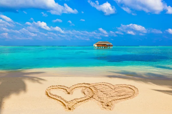 Drawing connected hearts on beach Stock Image