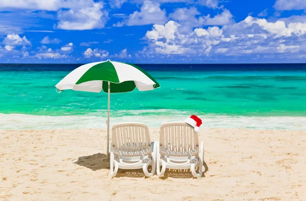 Chairs on tropical beach and Santa Claus red christmas hat — Stock Photo, Image