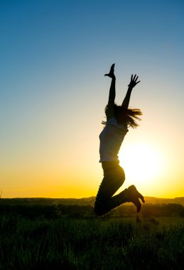 Güzel bir gün batımı önünde atlama siluet kadın