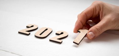 Yeni yıl 2021 konsepti. Kadın eli ahşap masaya 2021 numara koyuyor.