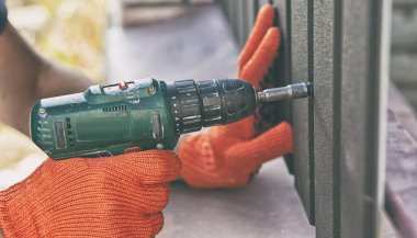 İşçi çiviyi metal çitlere vidalıyor.