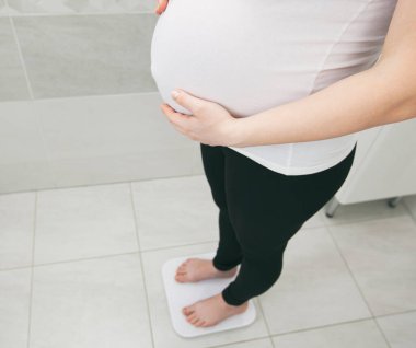 Hamile bir kadın banyo terazisinde tartılır.