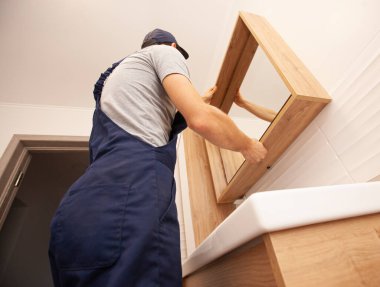 İşçi aynayı banyoya yerleştirir.