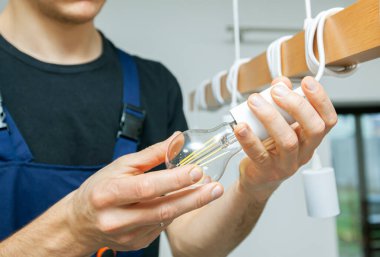 Elektrikçi kurşun ampulleri avizeye yerleştiriyor.