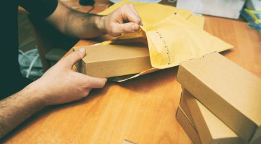 Adam ürünü sarı zarfa koyuyor.