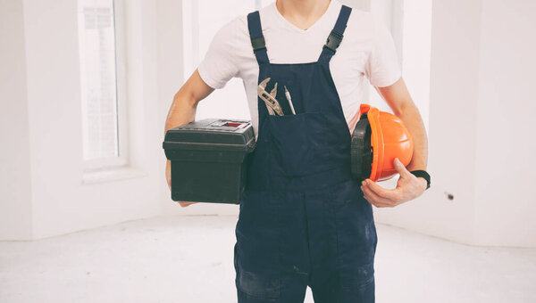 The repairer holding the toolbox in the the room being renovated