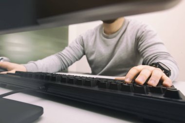 Adam ofisteki bilgisayarla çalışıyor.