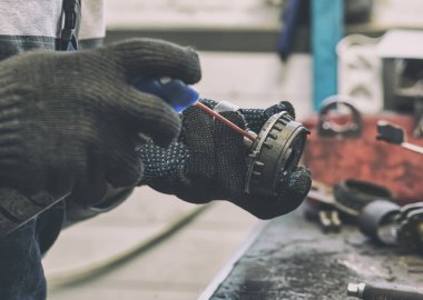 Tamirci araba parçalarından birini tamir ediyor. 