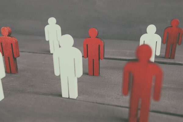 Два типа деревянных людей на деревянном столе: красный и белый