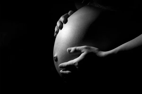 Těhotná žena břicho v temnotách — Stock fotografie