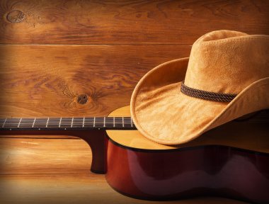 Guitar and cowboy hat on wood background