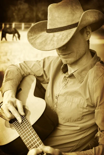 Guapo vaquero en sombrero occidental tocando la guitarra — Foto de Stock