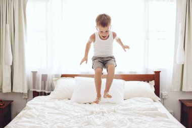 Çocuk yatakta zıplıyor.